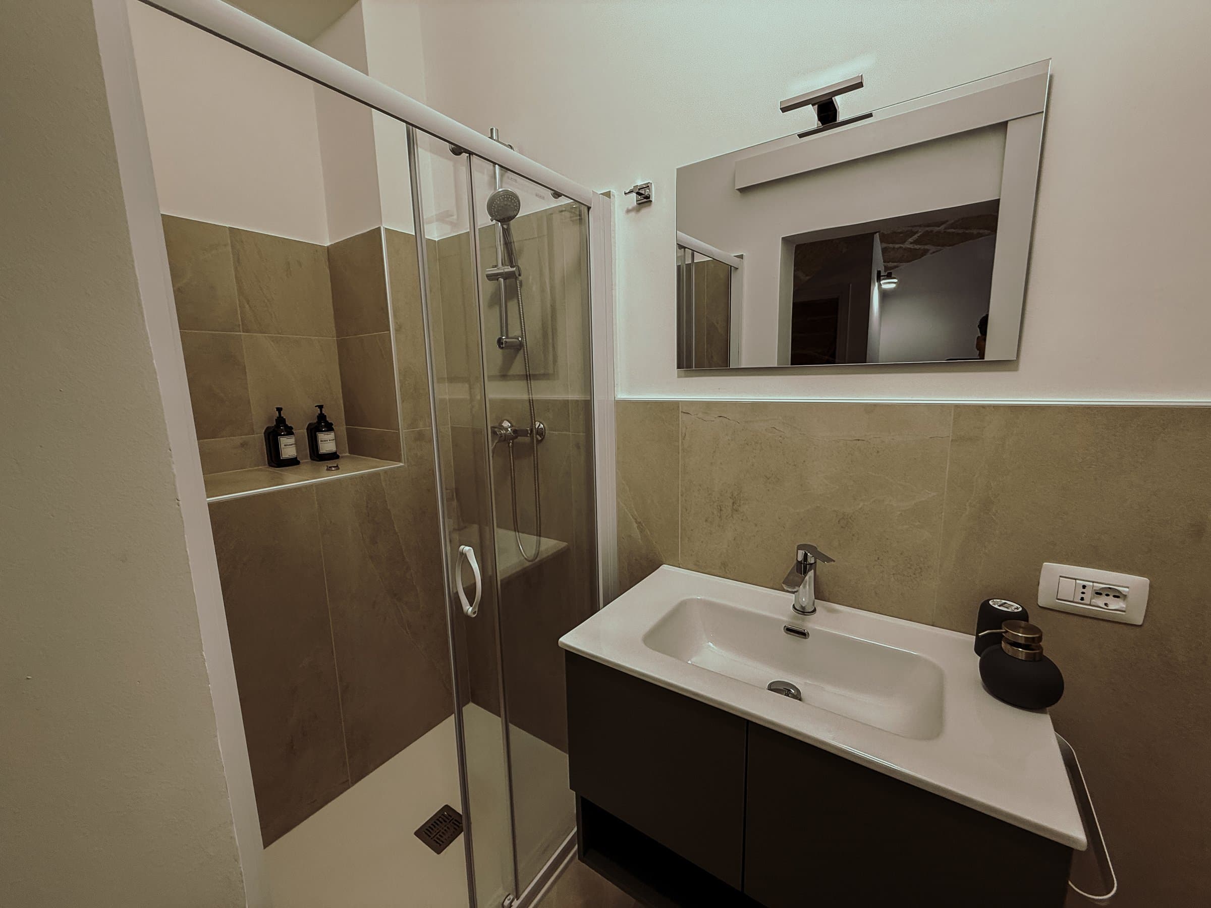 Bagno con doccia, lavabo e specchio
