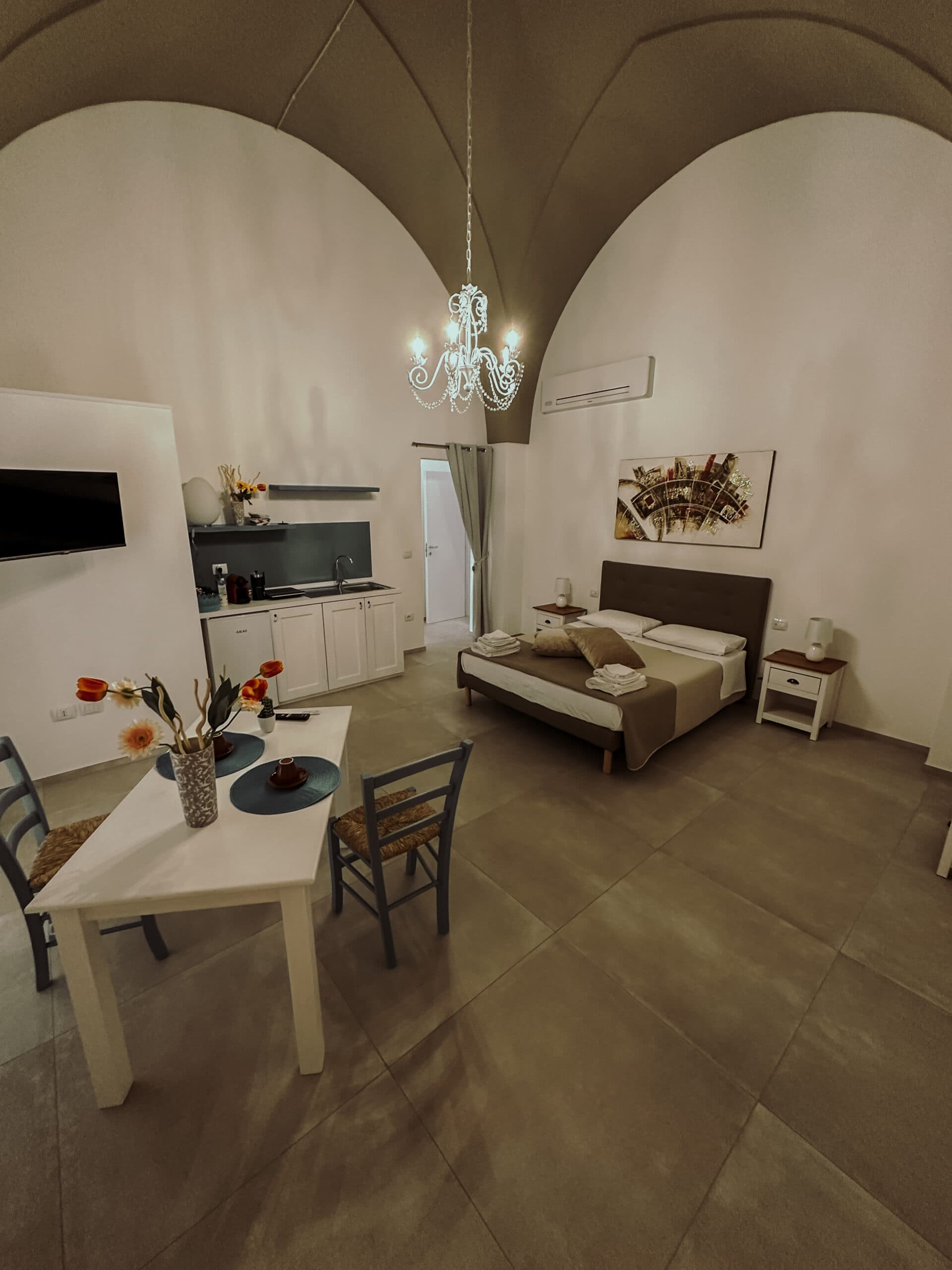 Camera con letto matrimoniale, angolo pranzo e soffitto a volta